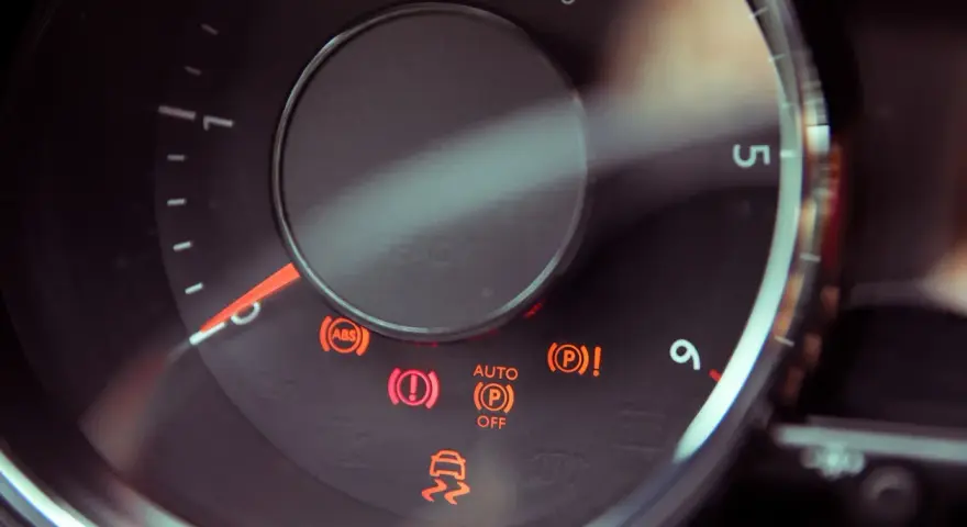 Dashboard lights illuminate, including ABS, brake warning, and a car skidding, indicating a potential issue with the slip indicator light.