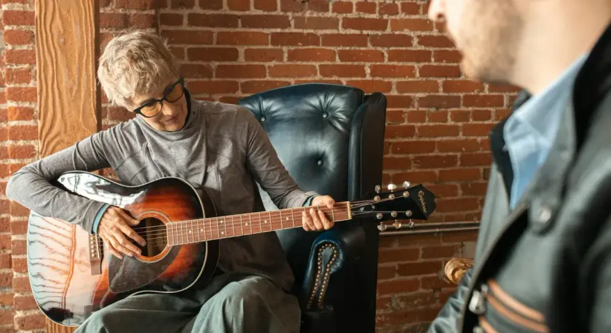 Kobieta gra na gitarze w szkole muzycznej dla dorosłych. Lekcja z nauczycielem.