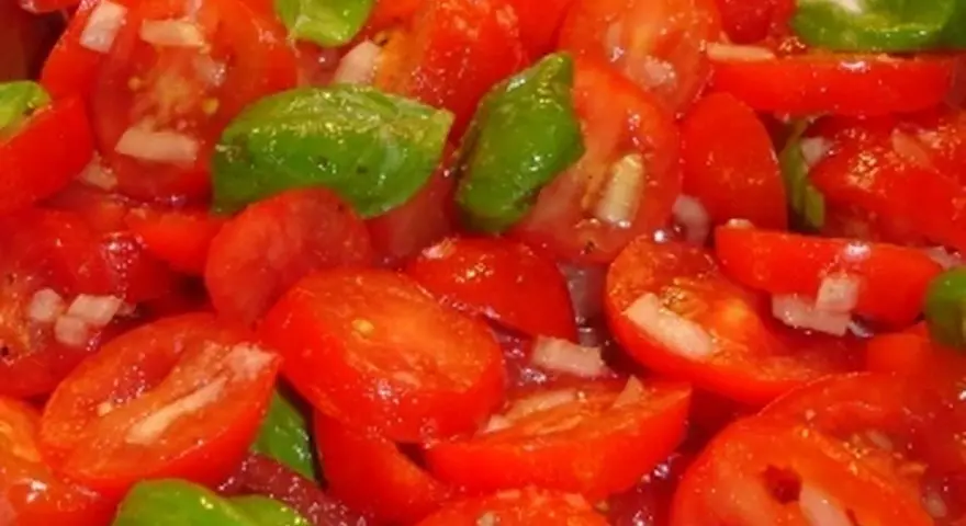Frischer Tomatensalat mit Zwiebeln und Basilikum, bereit für ein leichtes Tomatensalat Dressing.