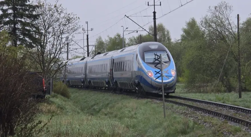 Srebrno-niebieski pociąg Pendolino jedzie po torach. W tle drzewa i słupy trakcyjne. Może to opóźnienie pociągu zwrot?