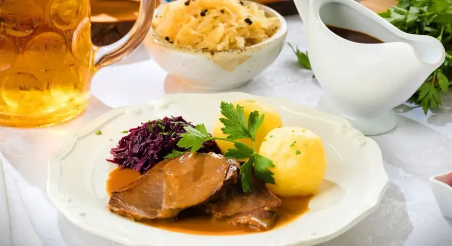 Deftiger Schweinebraten mit Klößen, Rotkohl und Sauerkraut. Dazu passt ein kühles Bier.