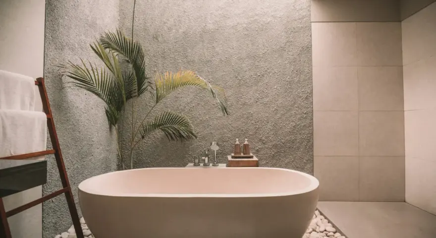 Ett modernt badrum med fristående badkar, en grå texturerad vägg och en palm. Perfekt för att renovera badrum och skapa en spa-känsla.