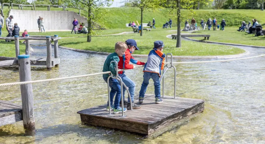 Drei Jungen auf einem Floß im Wasserspielplatz, der an ein Schiffshebewerk erinnert.