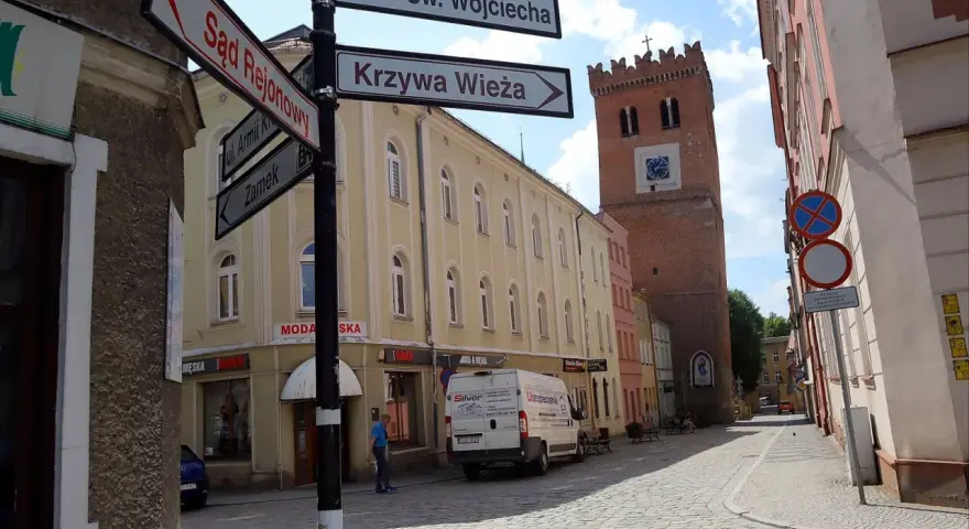 Ulica z wieżą i drogowskazami do Sądu Rejonowego, Krzywej Wieży i Zamku. Odkryj mało znane miejsca na Dolnym Śląsku.