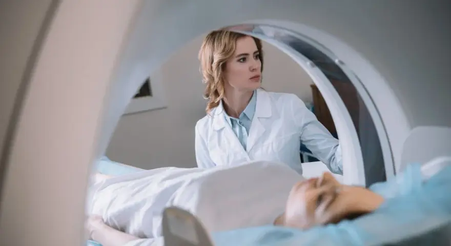 Lekarka nadzoruje badanie rezonans serca. Pacjent leży na stole diagnostycznym wewnątrz aparatu MRI.