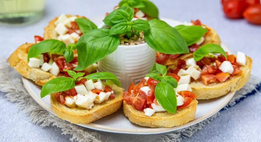 Bruschetta z pomidorami i mozzarellą – pyszny przepis na letnią przekąskę. Chrupiące grzanki z dodatkiem świeżej bazylii.