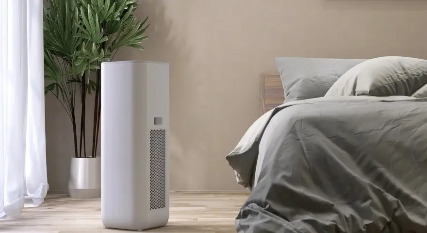 Un deumidificatore di notte, accanto a una pianta e un letto, crea un ambiente confortevole e salubre.
