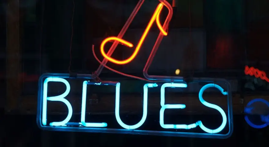 Néon bleu lumineux "BLUES" avec une note de musique rouge orangé au-dessus. L'ambiance parfaite pour une soirée blues.