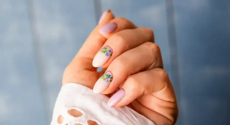 Delikatne, jasnoróżowe paznokcie z kwiatowym zdobieniem. Nawet przy łamliwych paznokciach można stworzyć piękny manicure.