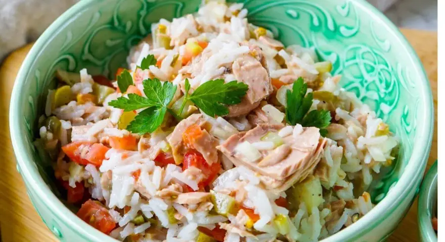 Reissalat mit Thunfisch, Tomaten und Gurken, garniert mit Petersilie, in einer grünen Schüssel. Ein leichter und leckerer Salat.