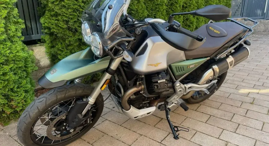 Zielony motocykl Moto Guzzi V85TT z silnikiem V, gotowy na przygodę.