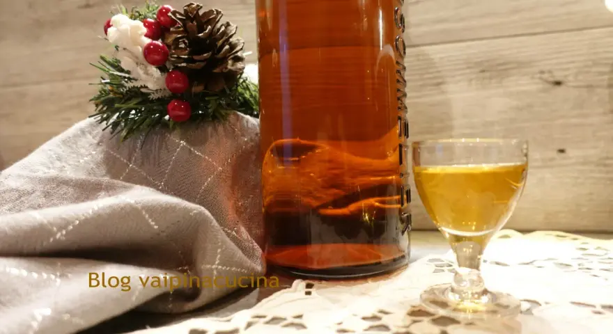 Liquore genziana ricetta: bottiglia ambrata, bicchierino dorato e decorazione natalizia.