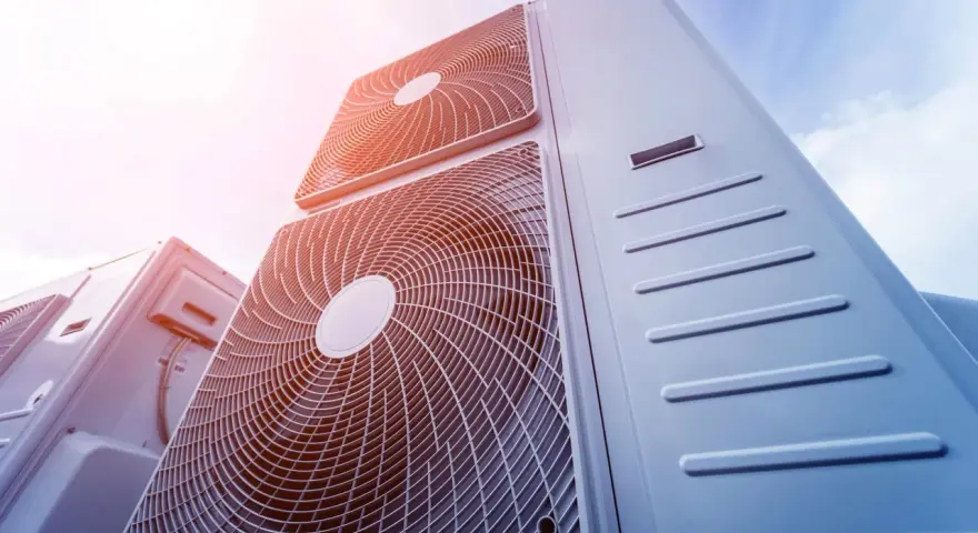 Pompa ciepła 8kw na ile metrów? Widok z dołu na kilka jednostek klimatyzacyjnych na tle błękitnego nieba.