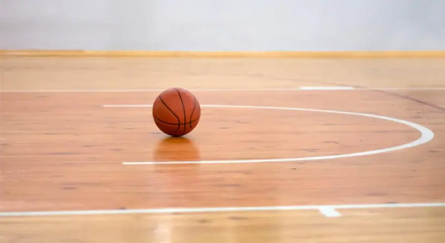 Balón de baloncesto sobre los pavimentos deportivos de madera pulida, listo para el juego.