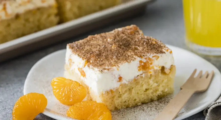Ein Stück saftiger Fantakuchen mit cremiger Füllung und Mandarinenstücken, bestreut mit Zimt. Perfekt für das Fantakuchen Rezept!