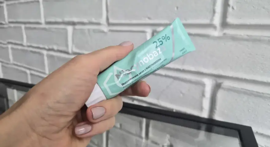Dłoń trzyma tubkę serum niacynobaza 25%. Wiele pozytywnych opinii o tym produkcie.