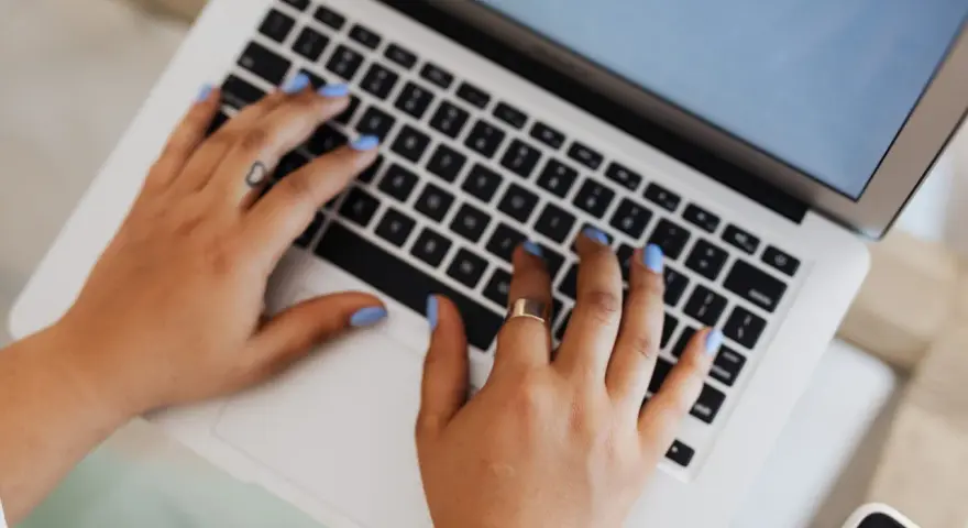 Mani che digitano su un laptop, forse per un corso di **università Pegaso**.