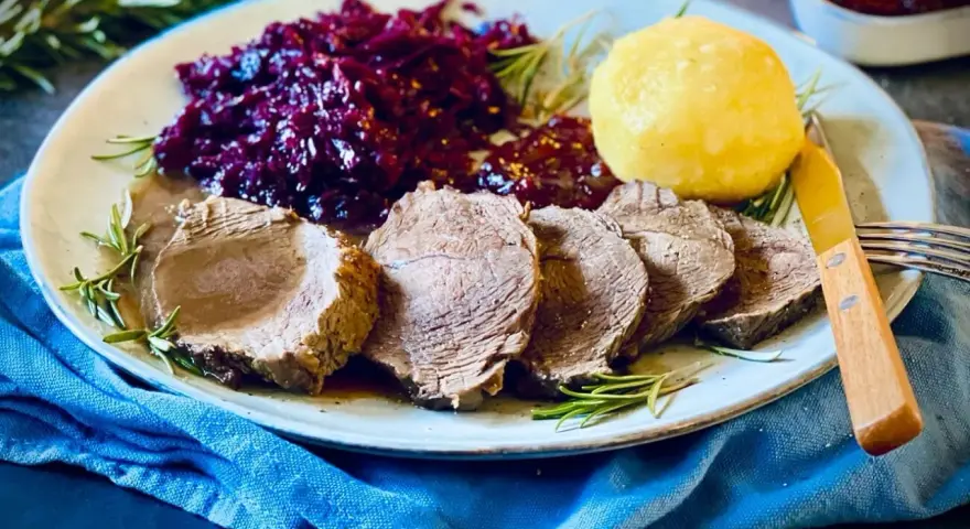 Saftiger Rinderbraten, serviert mit Rotkohl und Klößen – ein köstliches rinderbraten rezept für ein Festmahl.