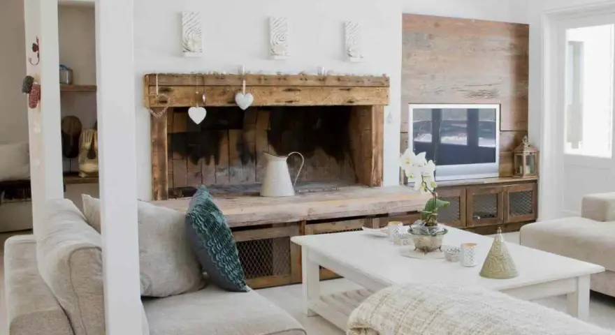 Un camino rustico con decorazioni a cuore e una brocca bianca, un'idea per come decorare un camino in stile country.