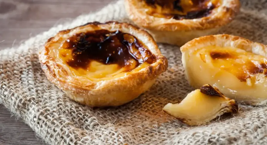 Tre krämiga portugisiska bakelser med karamelliserad yta, en klassiker inom portugisisk mat.