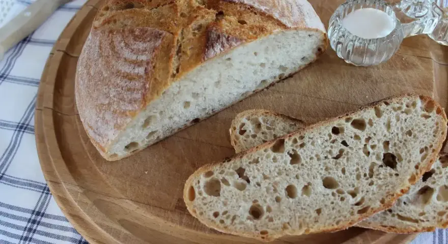 Chleb żytni na zakwasie, pokrojony w kromki, z solniczką na drewnianej desce.
