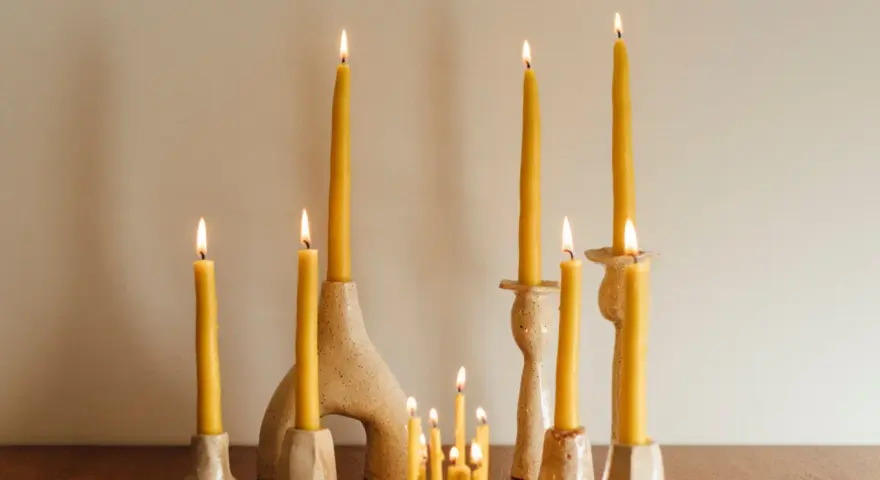 Velas amarillas de abeja en candelabros de cerámica. Una vela de palo santo para que sirve, ilumina el espacio con su suave resplandor.