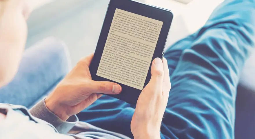 Osoba czyta książki na czytniku e-booków. Wygodny audiobook książki w cyfrowej formie.