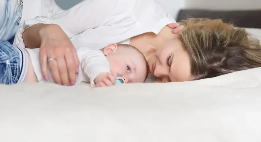 Mama tuli tuląca dziecko, ucząc się jak odkładać dziecko do łóżeczka, by spało spokojnie.