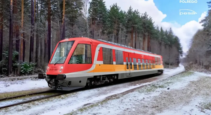 Czerwono-żółty pociąg EN 81-005 Polregio mknie przez zaśnieżony las.