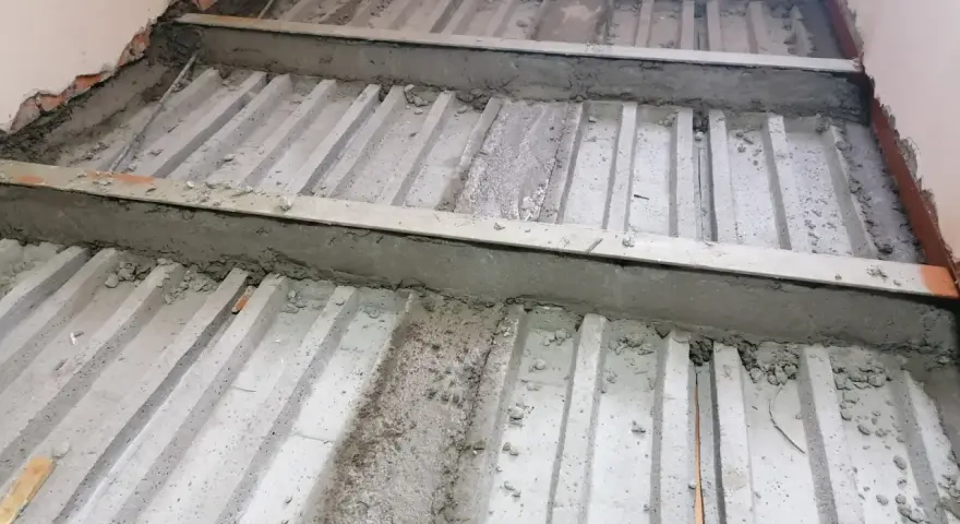 Prace nad tym, jak wzmocnić strop w starym domu. Widoczne belki stropowe i betonowanie.