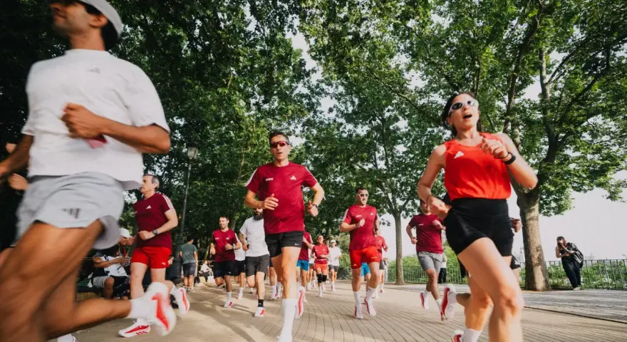 Corredores entrenan para el maratón Madrid 2026 en un día soleado, bajo la sombra de árboles frondosos.