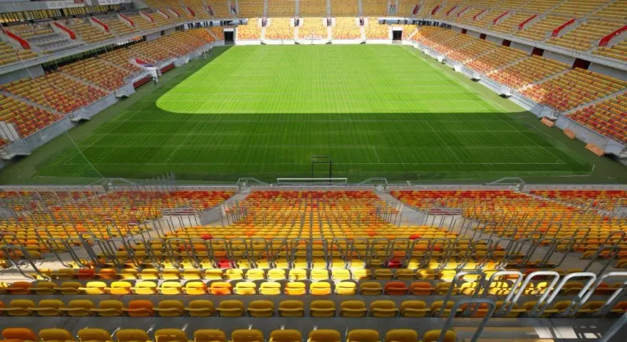 Pusta trybuna stadionu Jagiellonii, z żółtymi i czerwonymi siedzeniami. Pojemność obiektu robi wrażenie.