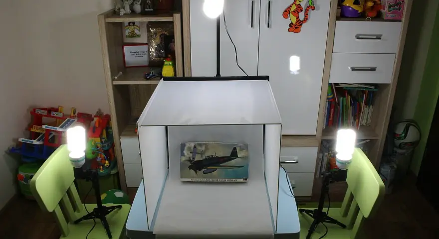 Domowy namiot bezcieniowy diy oświetla model samolotu. W tle regały z zabawkami i książkami.