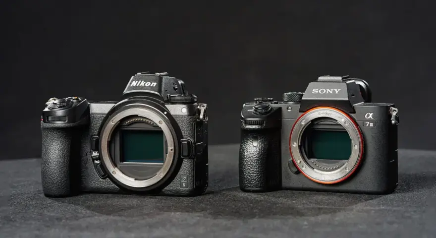 Dwie nowoczesne lustrzanki: Nikon z6 i Sony a7 III, stoją obok siebie na ciemnym tle.