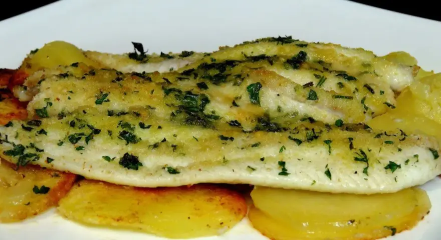 Delicioso lenguado al horno con patatas doradas y hierbas frescas.
