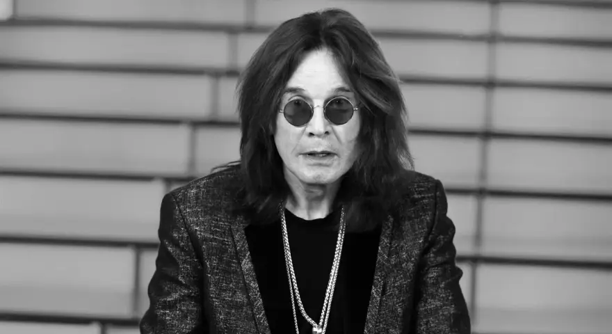 Ozzy Osbourne w okularach i błyszczącej marynarce, z naszyjnikami. Plotki o tym, że Ozzy Osbourne nie żyje, są fałszywe.