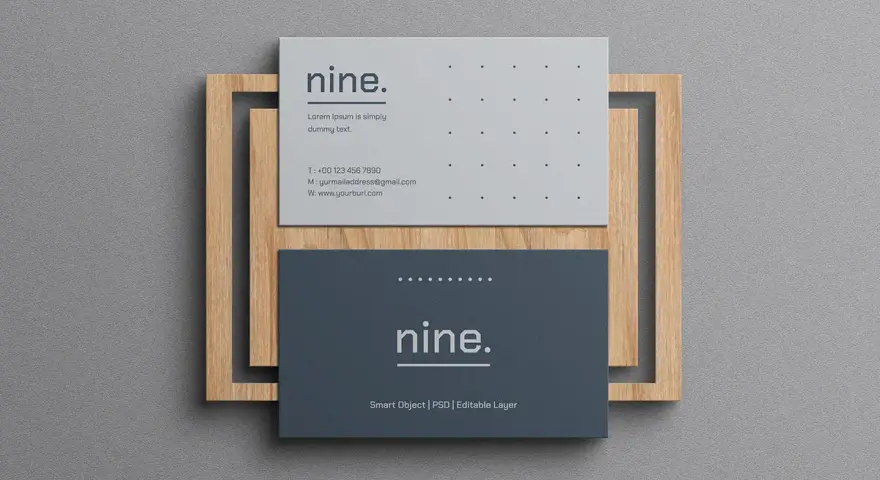 Dos tarjetas de visita minimalistas, una gris y otra azul oscuro, apiladas sobre un marco de madera.