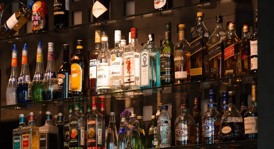 Różne rodzaje martini, szampanów i innych alkoholi na półkach baru.