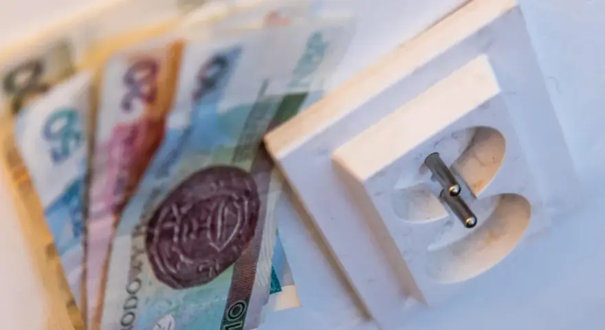 Polskie banknoty leżą obok gniazdka elektrycznego. Czy to symbolizuje rachunki za prąd? Billing co to?