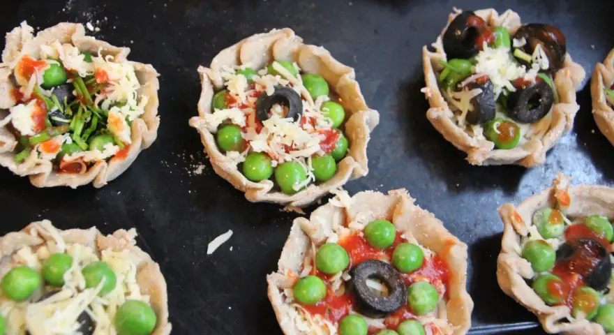 Mini pizze z groszkiem, oliwkami i serem, idealne na podwieczorek.