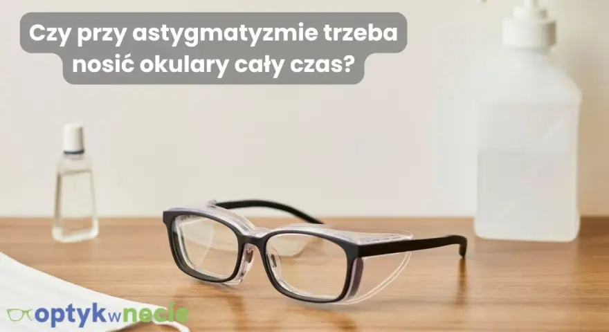 Okulary ochronne na drewnianym blacie, obok płynu do dezynfekcji i maseczki. Czy przy astygmatyzmie trzeba nosić okulary cały czas?