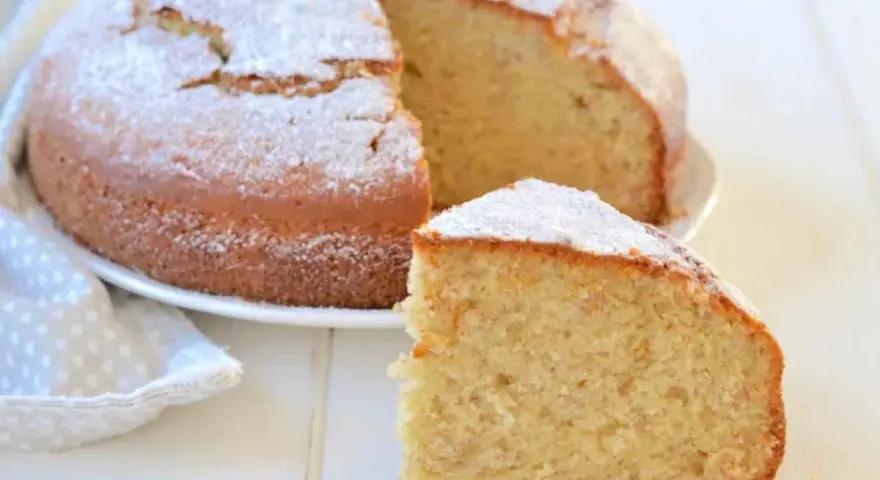 Una soffice torta di banane, spolverata di zucchero a velo, con una fetta tagliata per gustarla.