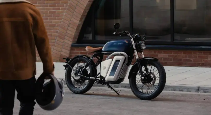 Eleganckie motocykle retro w miejskiej scenerii. Mężczyzna w brązowej kurtce trzyma kask, gotowy do jazdy.