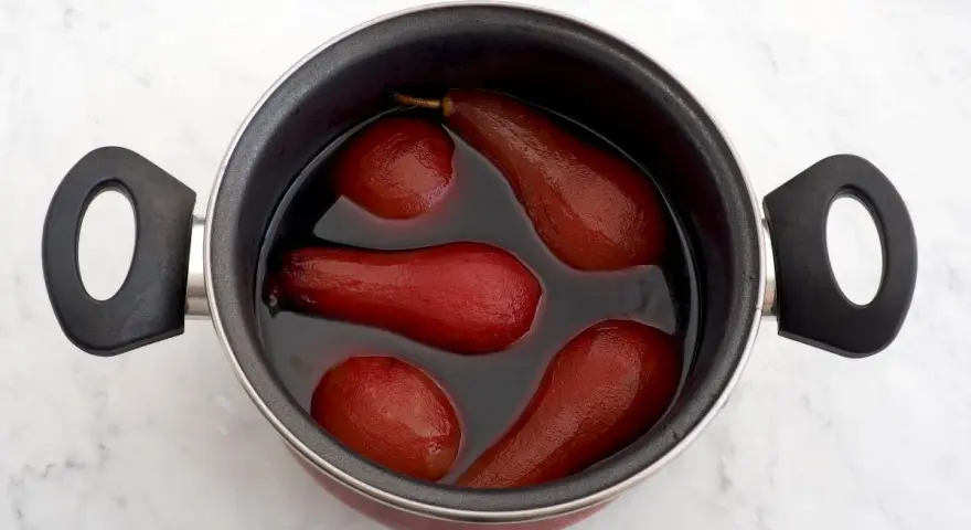 Olla con peras al vino tintas, listas para ser un postre delicioso.