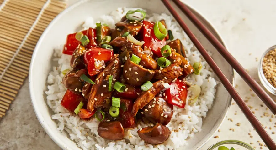 Schüssel mit Reis und einem köstlichen Chicken Teriyaki, garniert mit Frühlingszwiebeln und Sesam.