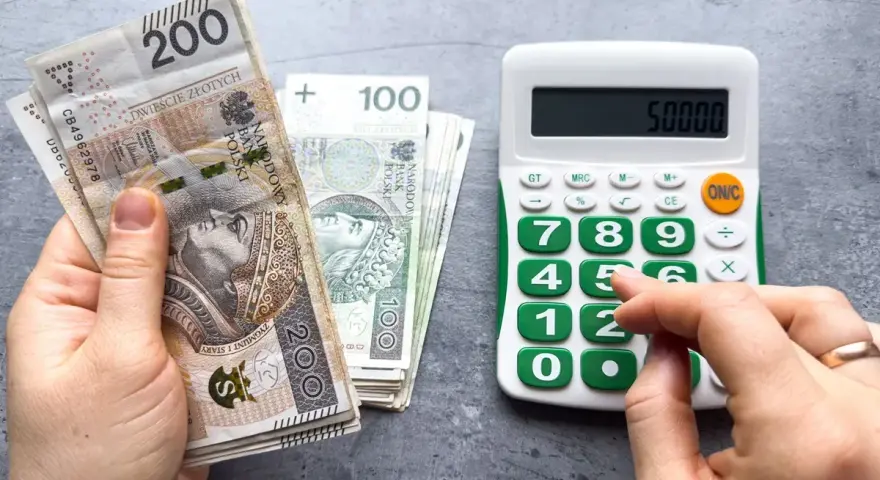 Ręka z polskimi banknotami 200 zł i 100 zł obok kalkulatora z wyświetloną kwotą 50000. Planowanie waloryzacji emerytury 2026.