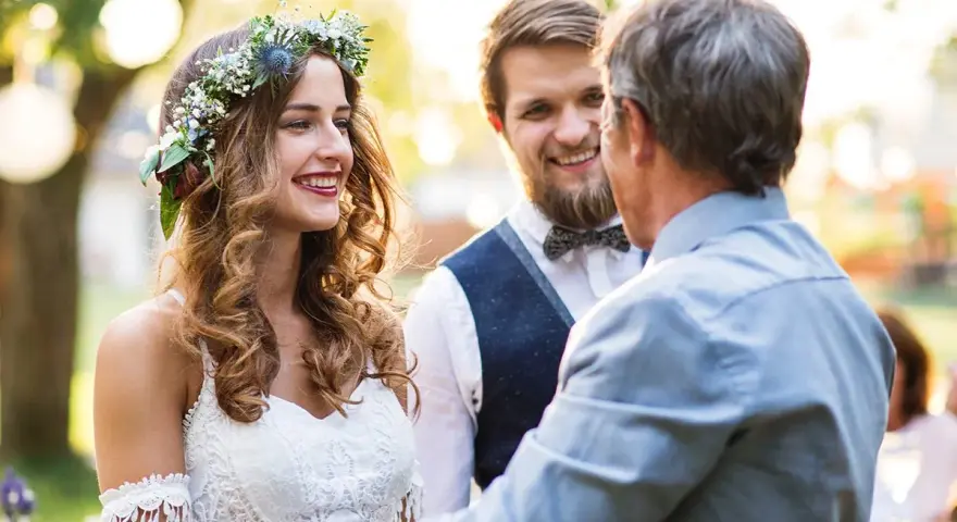 Panna młoda w wianku i pan młody słuchają ojca udzielającego im tradycyjne błogosławieństwo.