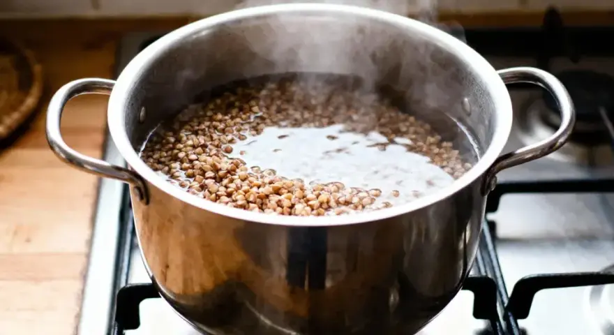 Une casserole de sarrasin bout sur la cuisinière, montrant comment cuire le sarrasin pour un repas sain.