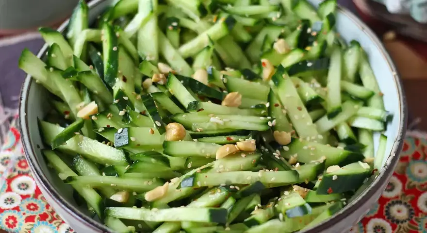 Una fresca insalata di cetrioli tagliati a julienne, condita con semi di sesamo, arachidi e peperoncino.