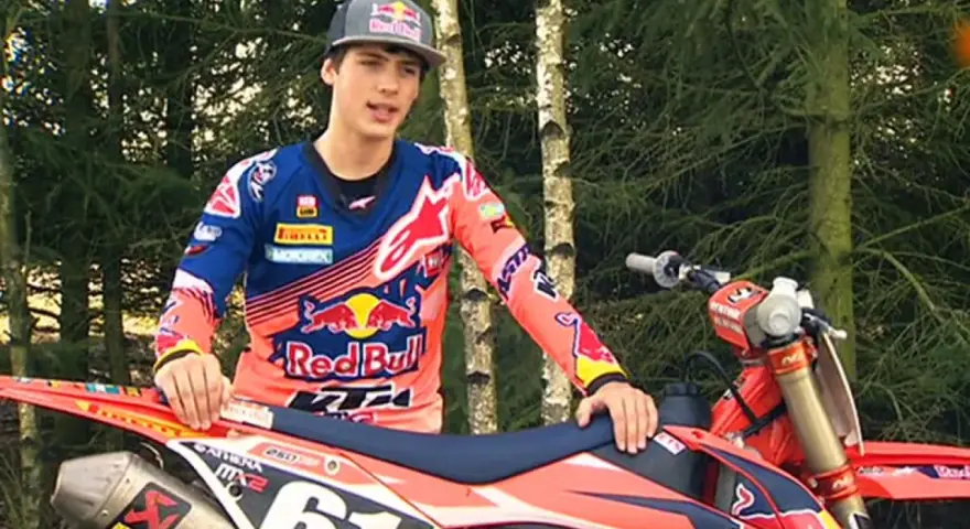 Jorge Prado, piloto de motocross, posa con su moto KTM en un bosque.